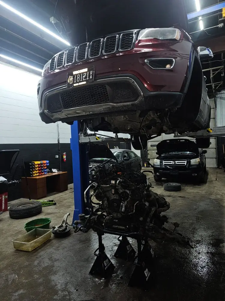 SUV on a lift with its engine lowered for repair